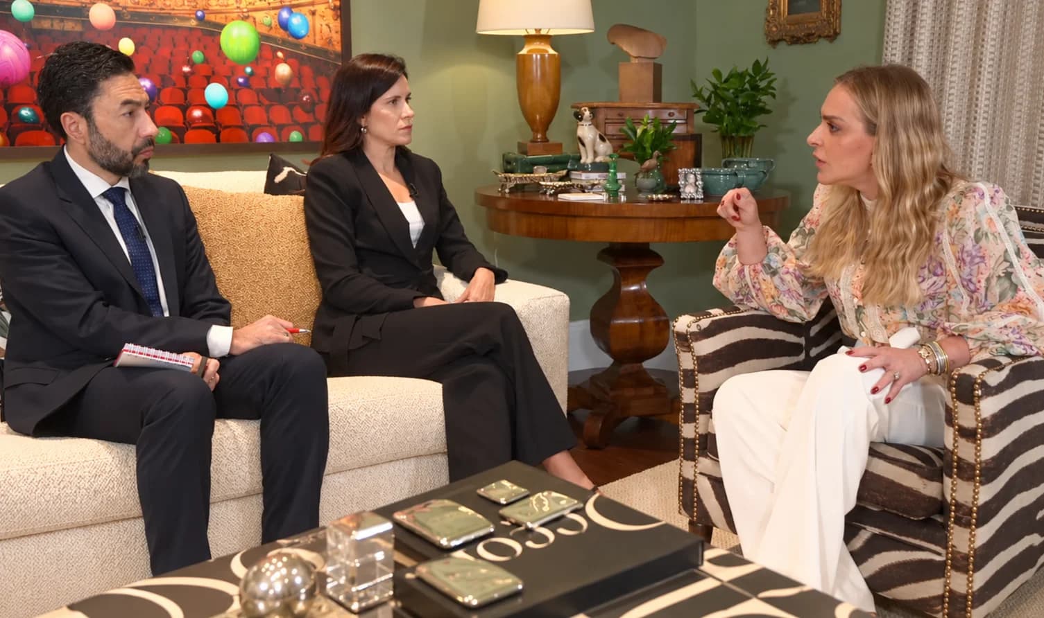 Três pessoas conversam em uma sala durante entrevista