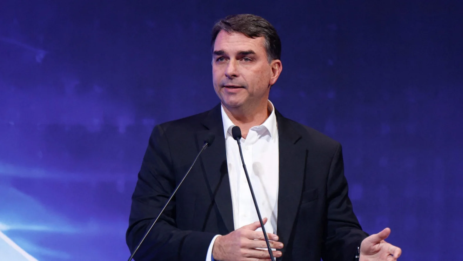 Flávio Bolsonaro discursa em púlpito com microfones